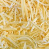 Fromage râpé utilisé comme ingrédient culinaire, symbole de l'essor des fromages dédiés aux pizzas, burgers, pâtes et autres plats du quotidien.