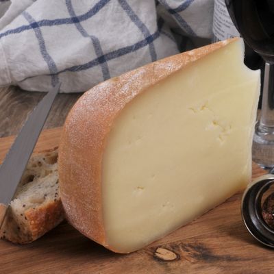 PDO Ossau-Iraty wheel cut on a wooden board, highlighting an iconic sheep’s milk cheese from the French Basque Country and Béarn regions.