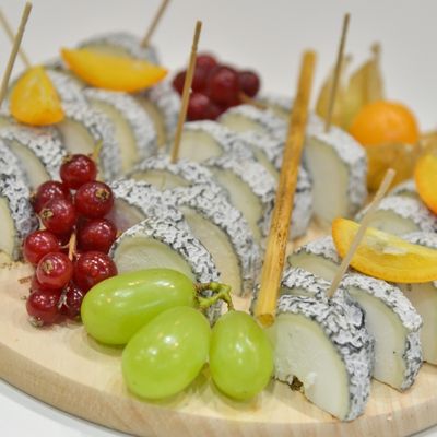 Slices of PDO Sainte-Maure de Touraine cheese served on a tasting platter with grapes and citrus fruits during a French cheese tasting event.