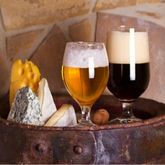 Verres de bière blonde et de bière brune accompagnés d’une sélection de fromages sur une table rustique, mettant en valeur les accords entre bière et fromage.