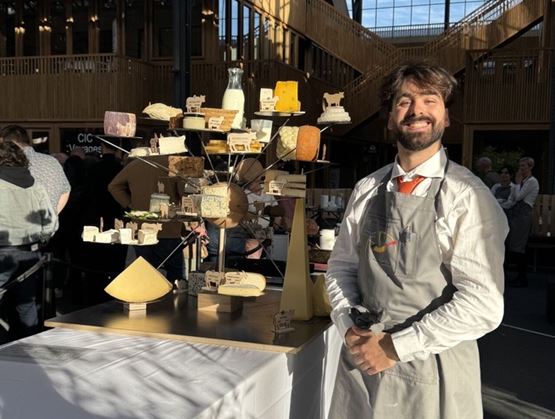 Léo Begin standing beside an artistic cheese display after winning the Premier Fromager de Belgique title in Brussels