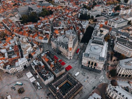 Vue aérienne d’une ville avec une grande place centrale entourée de bâtiments historiques et de rues animées.