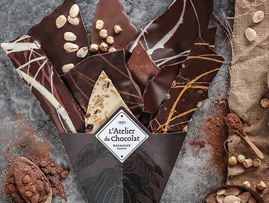 Assortiment de tablettes de chocolat artisanal avec noisettes et éclats, présenté dans un emballage.