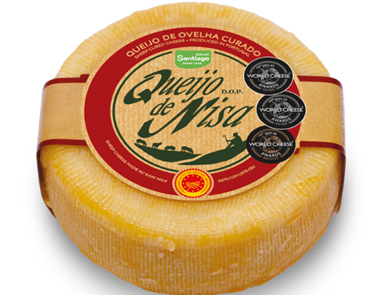 Portuguese Queijo de Nisa DOP cheese, with a yellow rind and red label, adorned with medals from the World Cheese Awards.