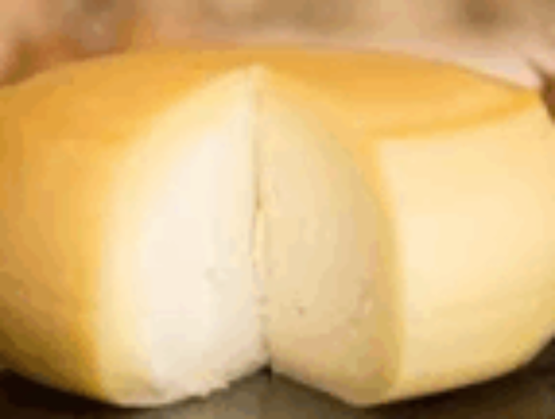 Whole Portuguese cheese with a pale yellow rind, cut open to reveal a white paste.