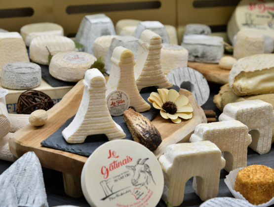 Plateau de fromages artisanaux aux formes variées et créatives, disposés sur des planches en bois.