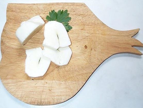 Fromage à pâte filée tranché sur une planche en bois, texture lisse et blanche, illustrant le travail du caillé filé.