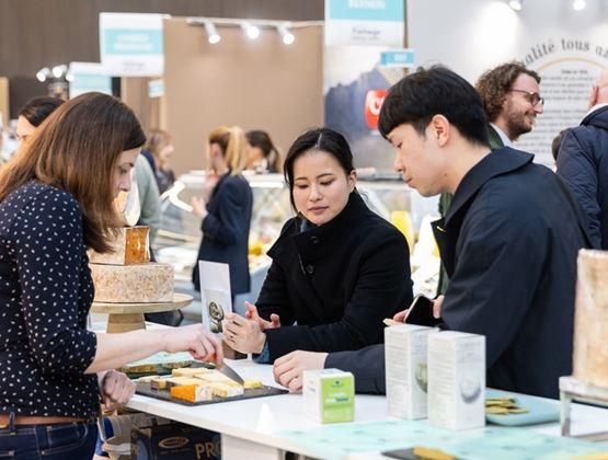 Visiteurs dégustant des fromages sur un stand lors d’un salon professionnel.