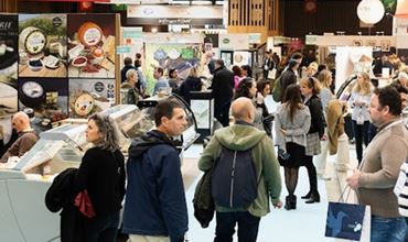 Visiteurs échangeant avec des exposants sur un salon professionnel de produits alimentaires.