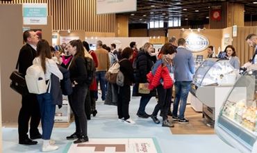 Visiteurs échangeant avec des exposants et découvrant des produits sur les stands d’un salon professionnel.