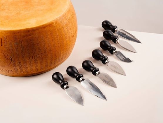 Meule de Parmigiano Reggiano accompagnée de couteaux à fromage présentés lors d’un salon professionnel.