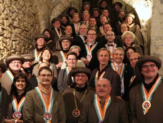 Groupe de personnes posant dans un escalier en pierre, portant des médailles et des tenues de cérémonie.