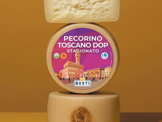Meules de Pecorino Toscano DOP Stagionato empilées, avec une étiquette colorée au centre.