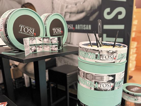 Stand de fromages Tosi présentant des meules de gorgonzola et un comptoir décoré aux couleurs de la marque.