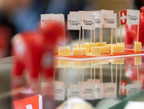 Cubes de fromage présentés sur des pics avec petits drapeaux suisses lors d’un événement professionnel.