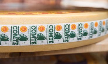 Gros plan sur une meule de fromage portant une bande de marquage du Comité de certification.