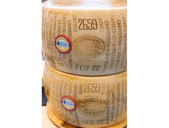 Deux meules de Parmigiano Reggiano empilées, portant les marquages officiels et les labels G. Cravero.