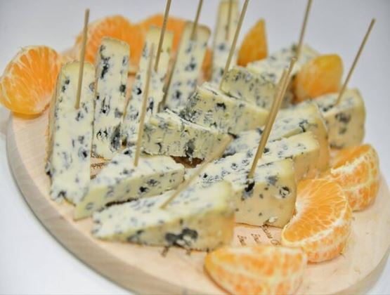 Morceaux de fromage bleu servis sur un plateau avec des quartiers de clémentine.