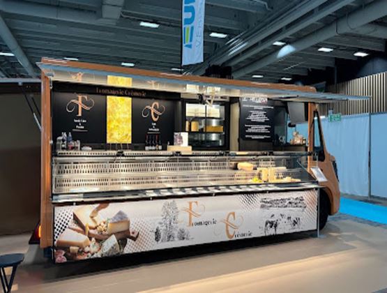 Stand mobile de la Fromagerie Crèmerie présentant des fromages dans une vitrine réfrigérée.
