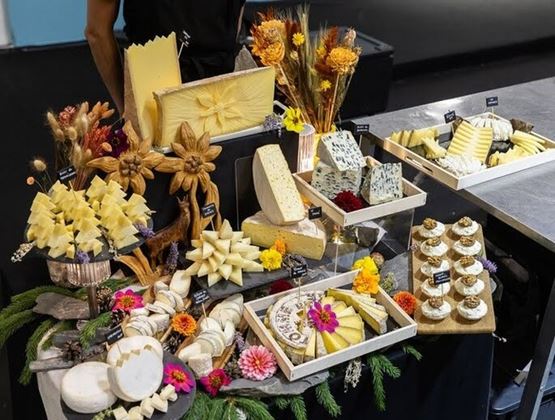 Plateau de fromages artistiquement dressé avec fleurs, découpes sculptées et présentations variées.
