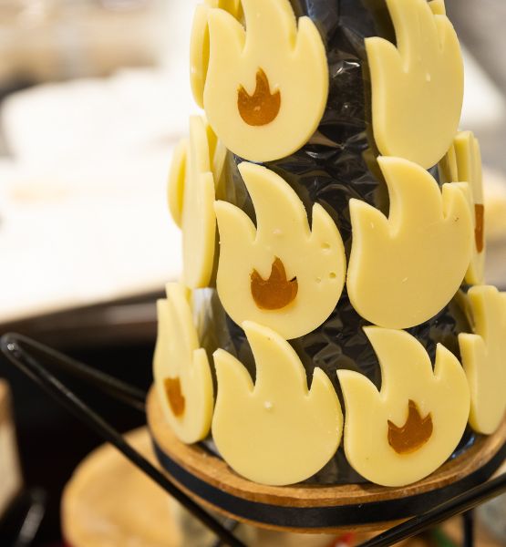 Decorative cheese creation with yellow flame shapes arranged on a black stand.