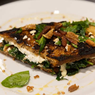 A grilled sandwich with spinach, goat cheese, and dried fruits.