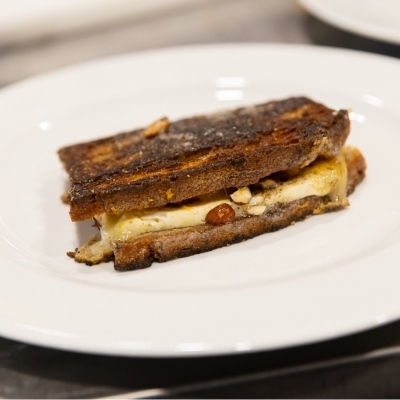 Un sandwich grillé avec du fromage fondu et des amandes.