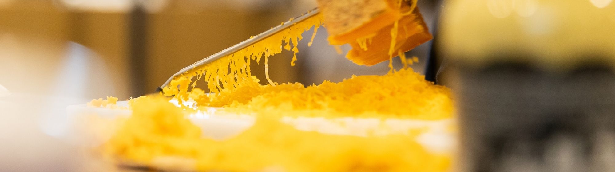 Un plan rapproché de fromage râpé, utilisé pour la préparation de plats lors d'un concours.