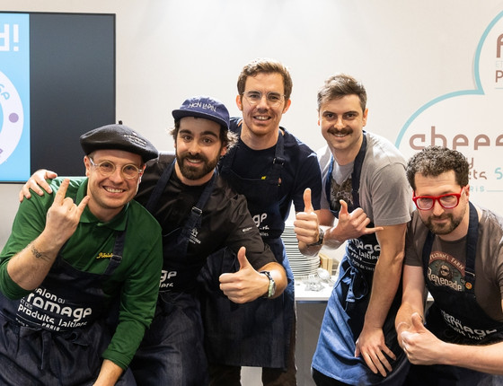 A group of chefs posing together with smiles, dressed in kitchen uniforms during a culinary event.